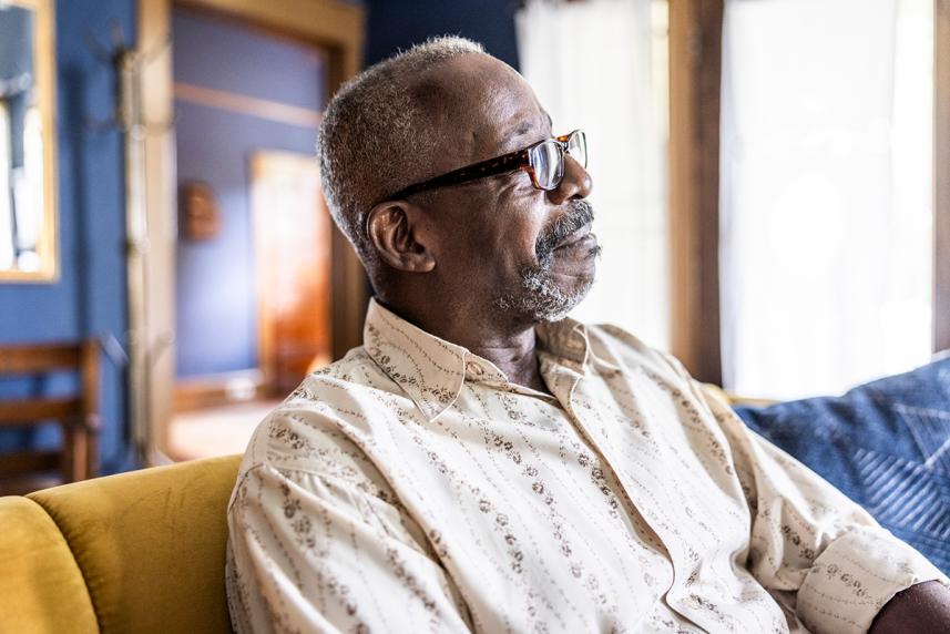 A man sitting, staring off to the side