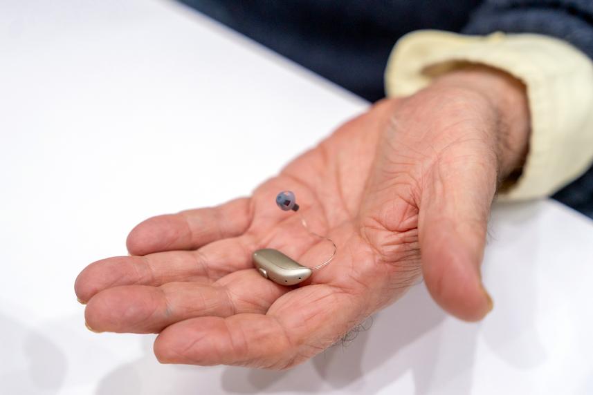 A hand holding a hearing aid