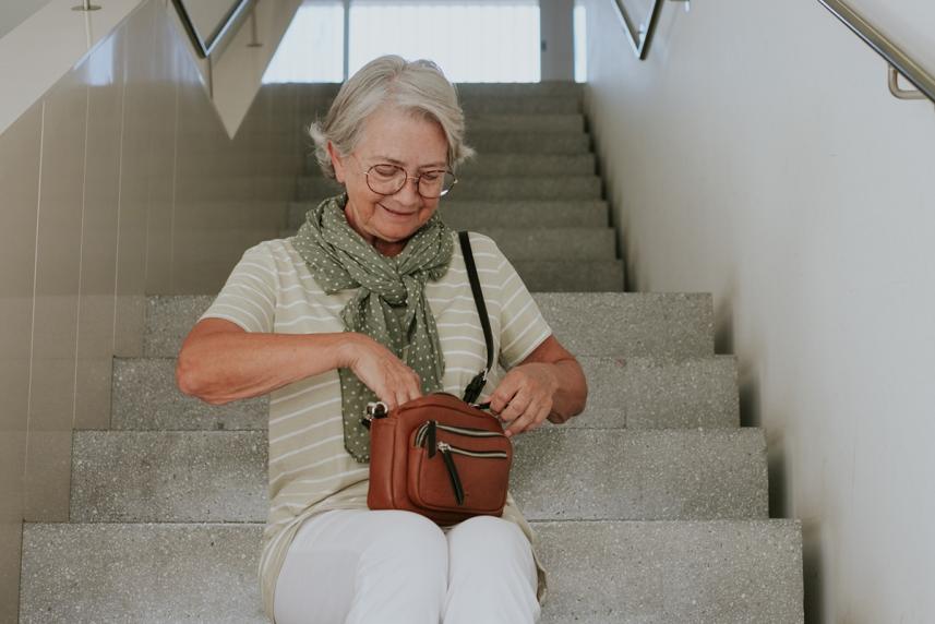 A woman looking through her purse, sitting on stairs