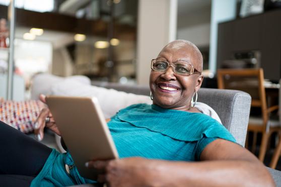 A woman holding a tablet and smiling at the camera